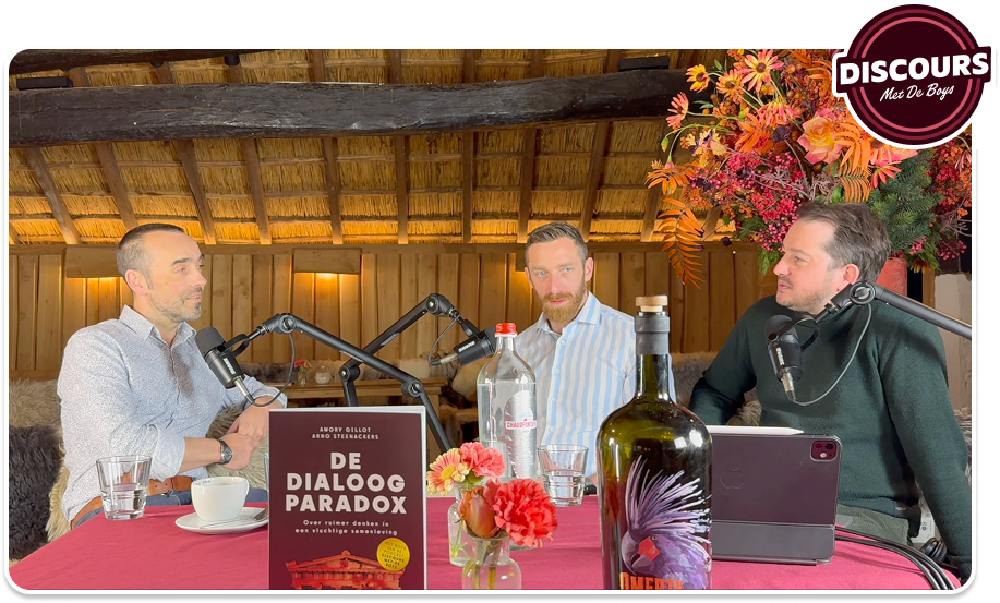 Drie hosts aan tafel in De Melkerij, met het boek De Dialoog Paradox en microfoons &mdash; een Discours-opname.